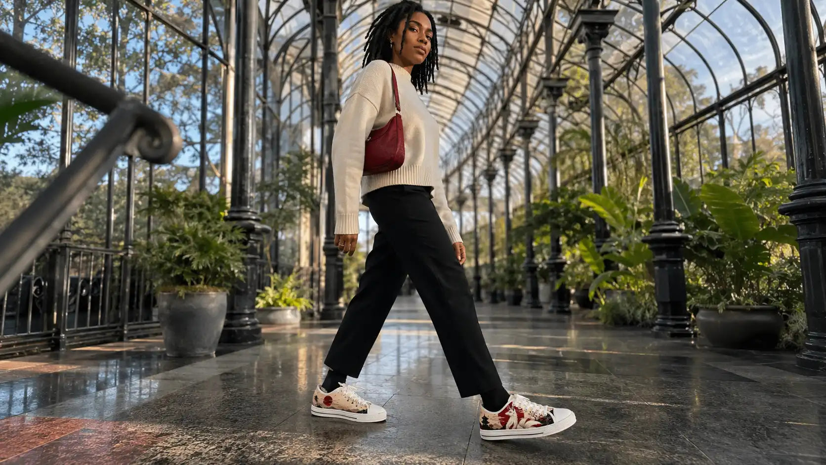 Gen Z woman wearing Kitsune Red Sun low-top sneakers with black ankle trousers and a cream knit in a glasshouse arcade.